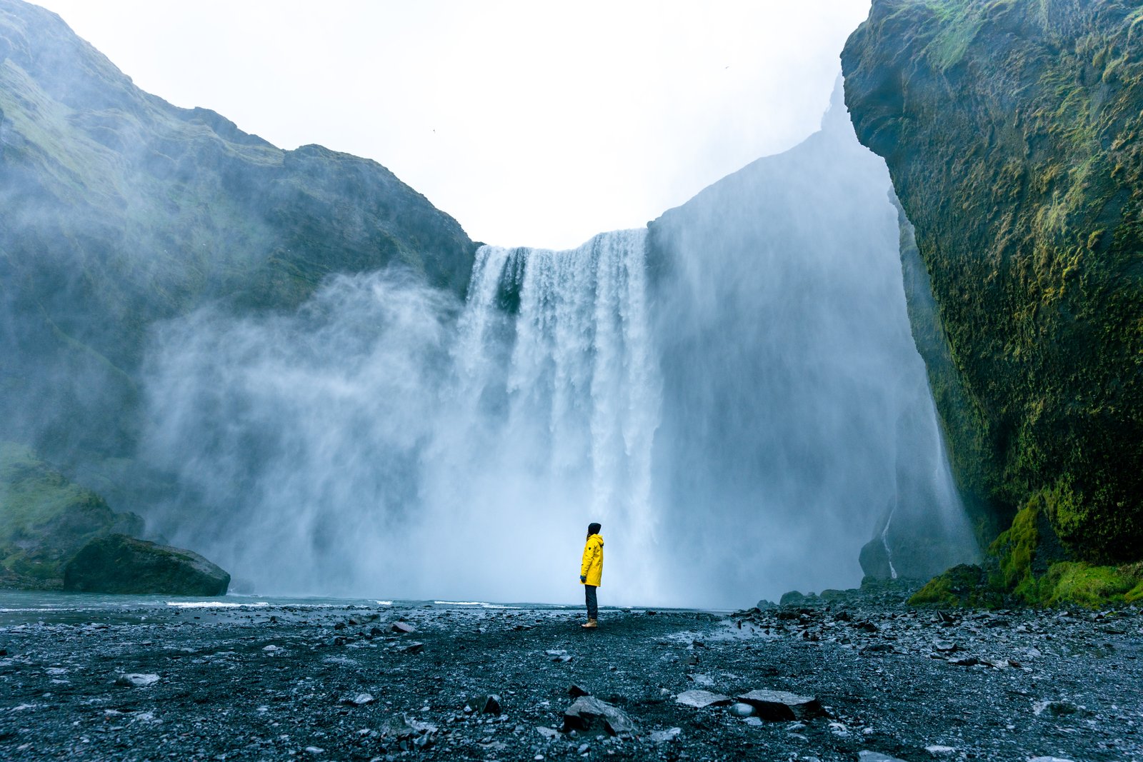 Kona í gulri kápu við Skógafoss