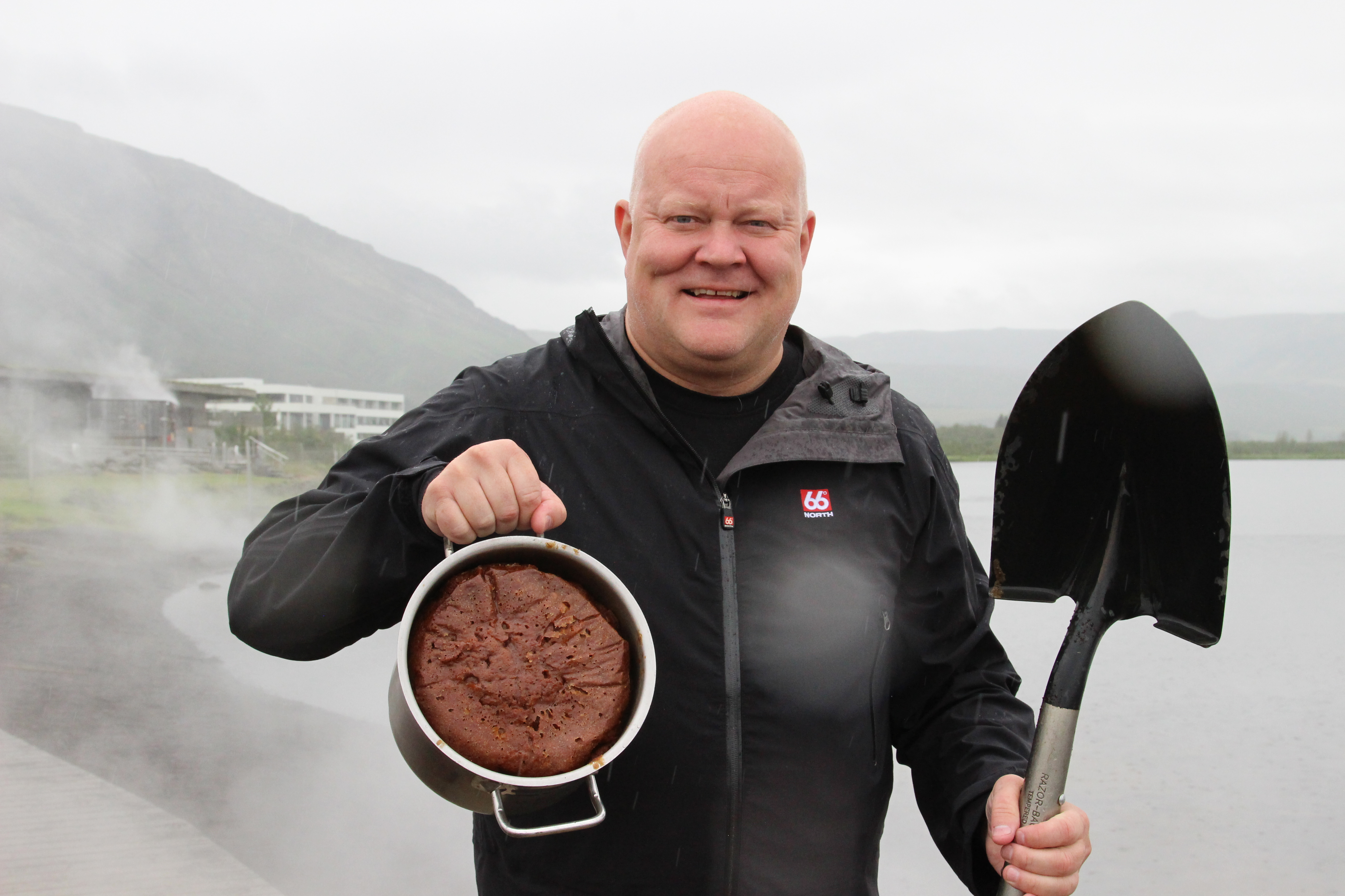 Rye bread baking in a geothermal hot spring A man holding up a pot with rye bread baked in a hot spring and a shovel